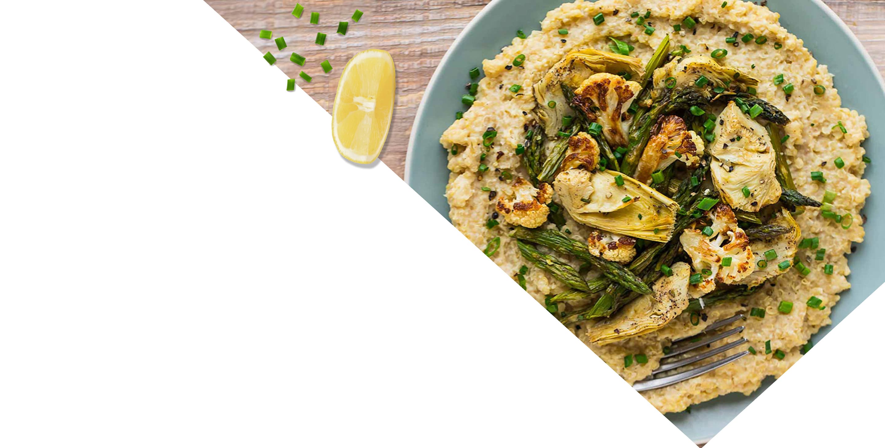 A plate of creamy risotto topped with roasted artichokes, asparagus, cauliflower, and chives, with a lemon wedge on the side.