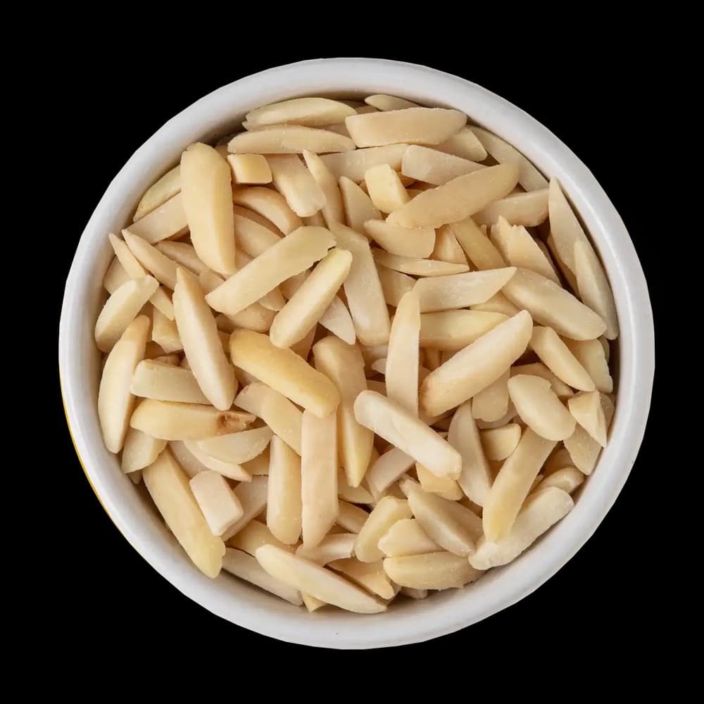 A white bowl filled with slivered almonds is shown against a solid black background.