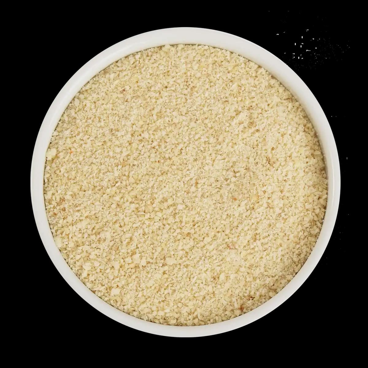 A white bowl filled with light-colored, finely ground breadcrumbs, pictured from above against a black background.