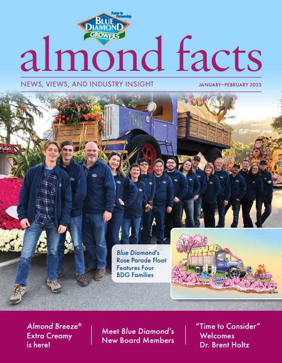 A group of people in matching jackets stand in front of a parade float decorated with flowers, featured on a magazine cover titled almond facts..