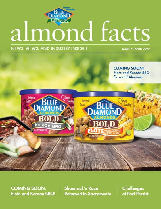 Two Blue Diamond almond containers—Korean BBQ and Elote—are displayed on a table with corn and peppers, on the cover of almond facts magazine, March-April 2022 issue.