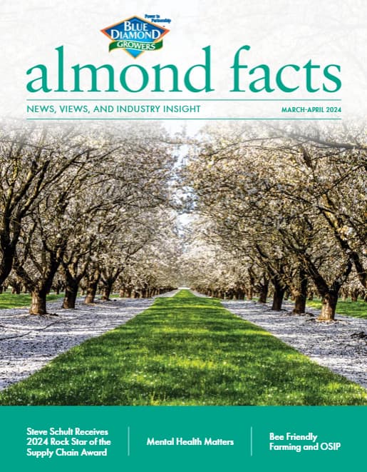 Rows of blooming almond trees line a pathway under a clear sky; magazine cover titled almond facts features articles on supply chain, mental health, and bee-friendly farming.