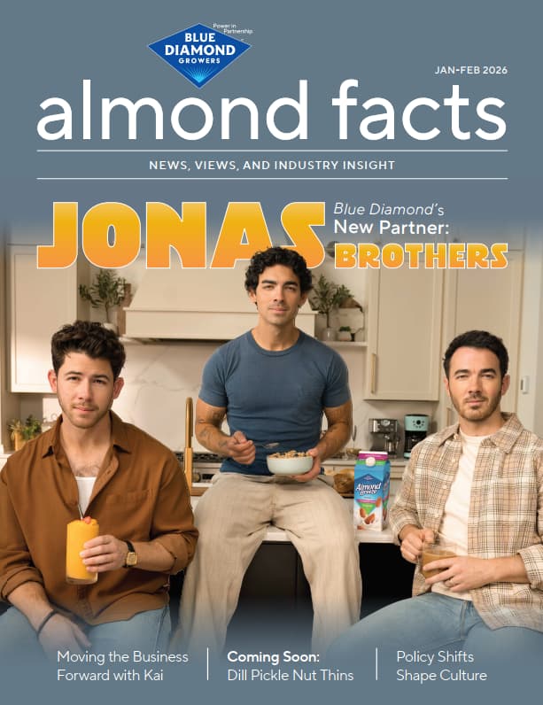 Three men sit in a kitchen holding food and drinks, with almond facts magazine masthead and Jonas Brothers: Blue Diamonds New Partner headline above them.