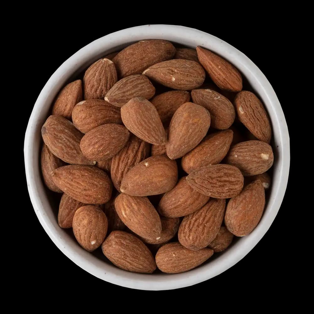 A white bowl filled with whole, unpeeled almonds sits against a solid black background.
