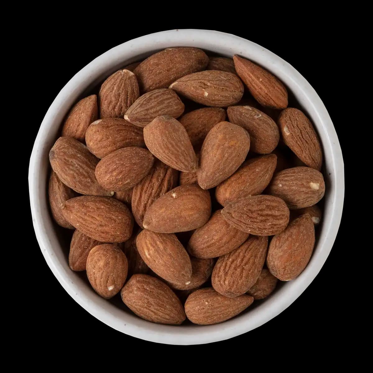 A white bowl filled with whole, unpeeled almonds sits against a solid black background.
