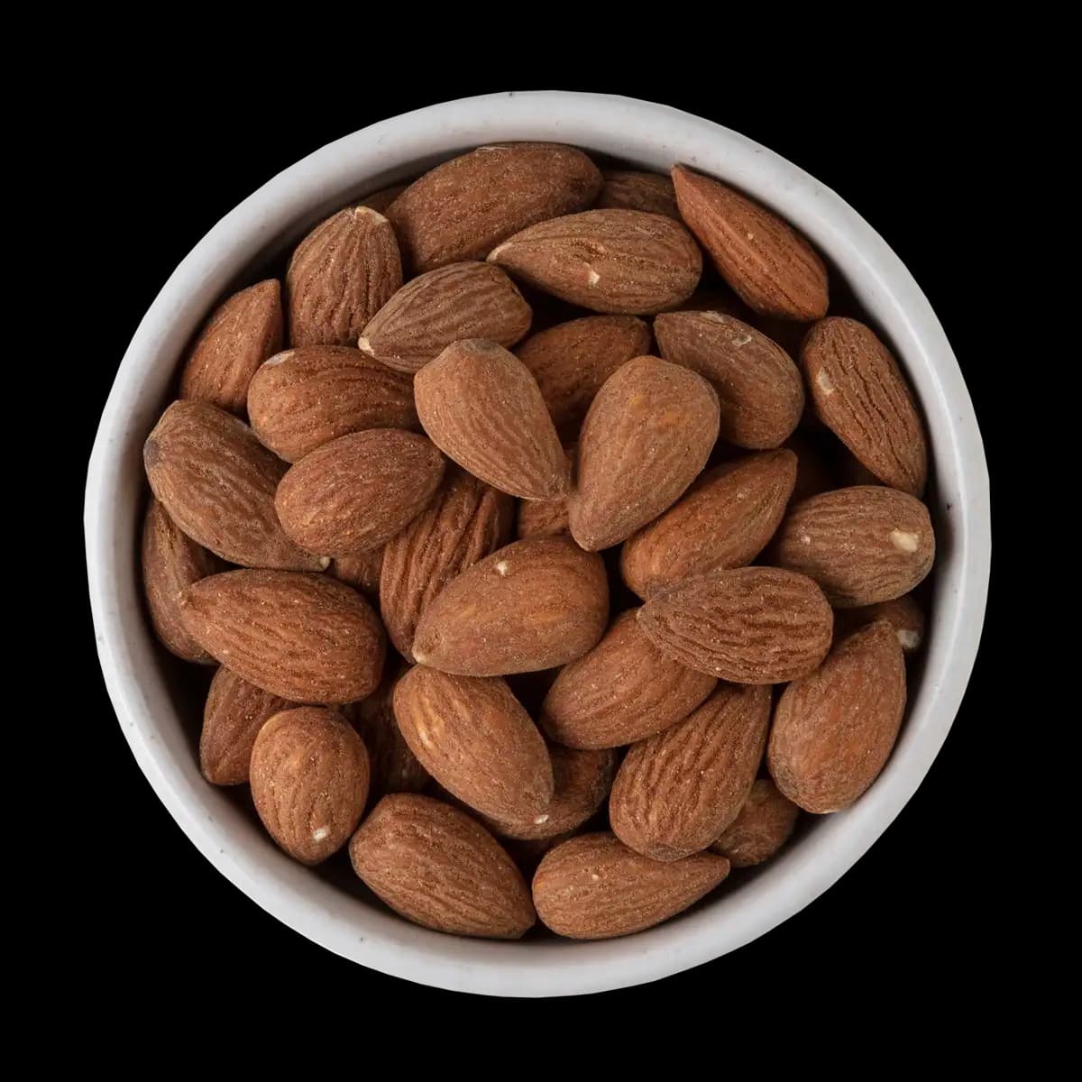 A white bowl filled with whole raw almonds, viewed from above against a black background.