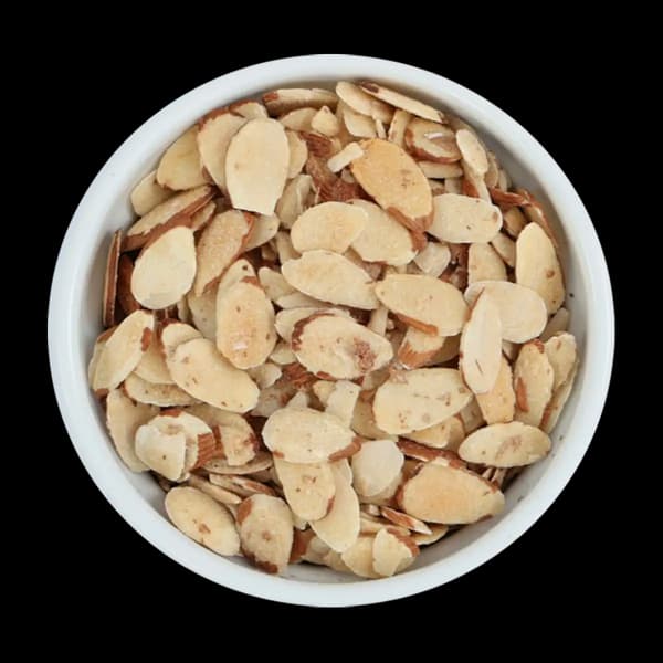 A white bowl filled with sliced almonds, photographed from above against a black background.